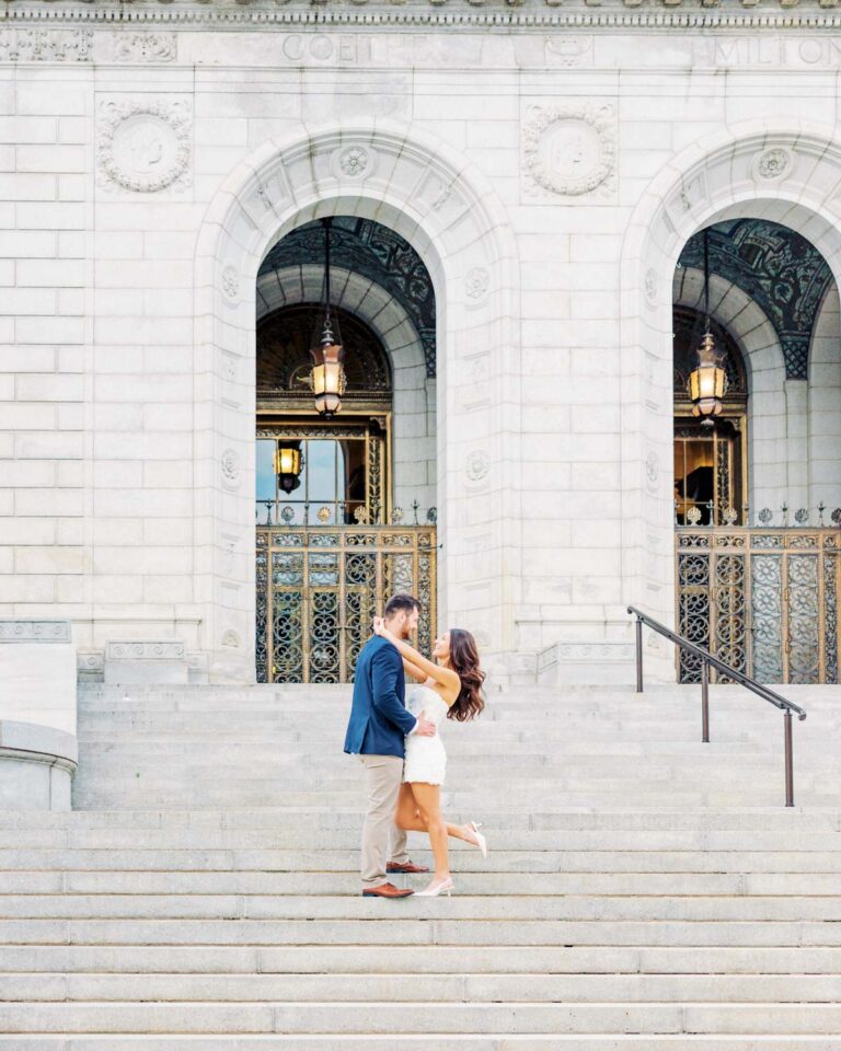 Engaged couple embracing on the steps of the Saint Louis Public Library during an engagement session.