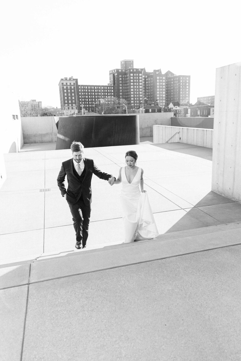 Groom gently holding his wife as they ascend the stairs at the contemporary art museum, with the Pulitzer Arts Foundation and the New Masonic Temple in the backdrop.