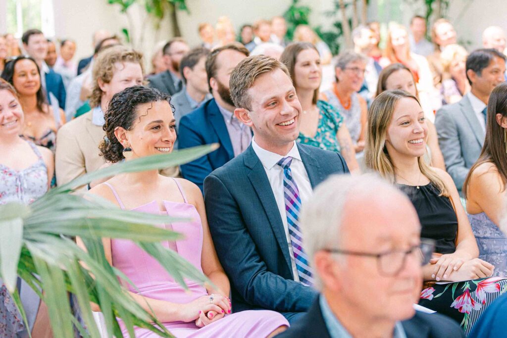 Guests dressed in colorful attire smiling during the ceremony as the bride's grandparents give advice.