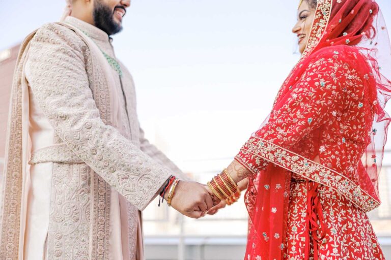 South Asian couple holding hands on a rooftop with a view of Pittsburgh city, captured by James Tananan, wedding photographer and videographer