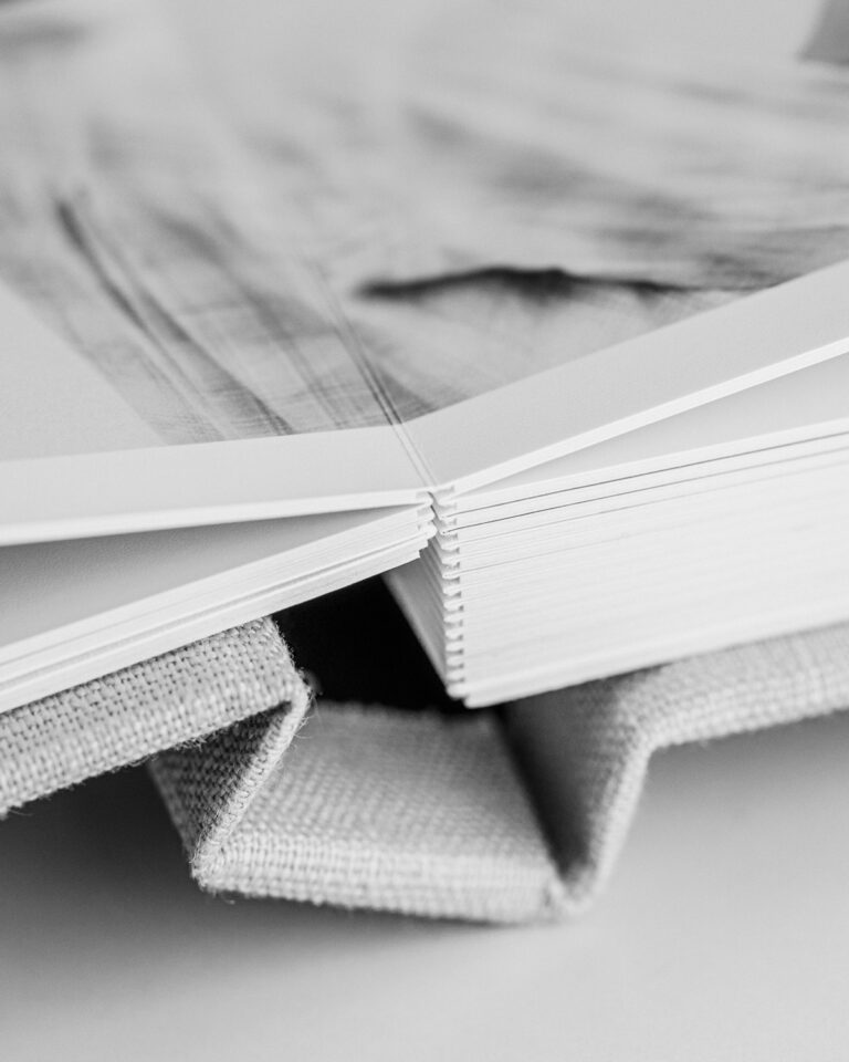 Close-up detail of a handcrafted wedding photo album with thick archival pages and linen cover.