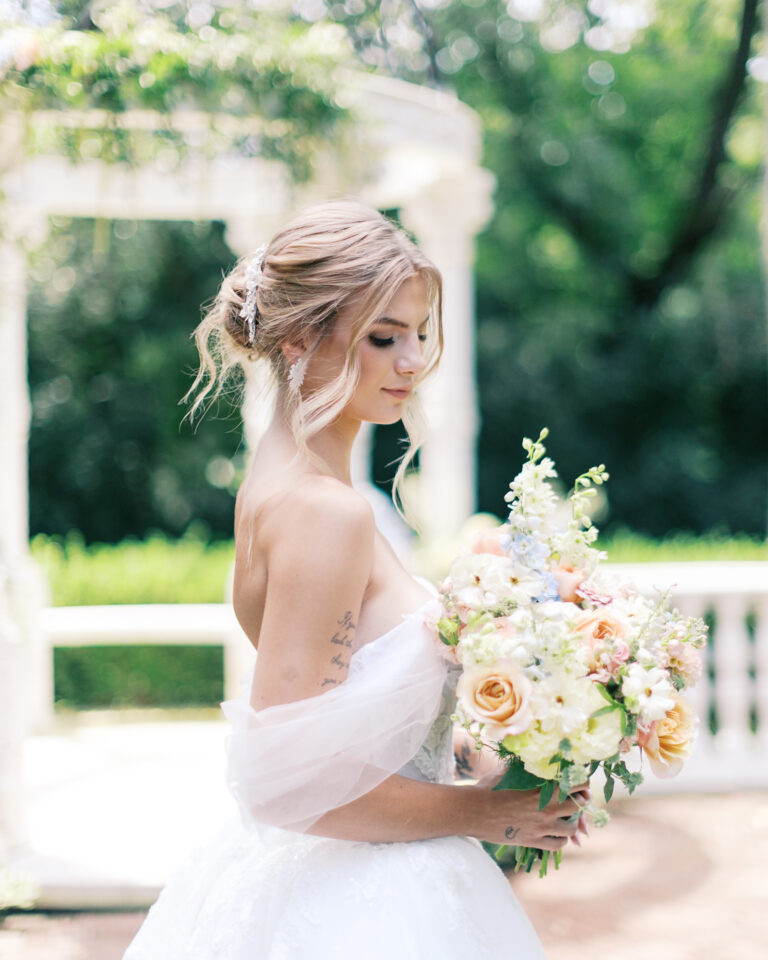 Bride holding a bouquet while wearing a wedding dress outdoors
