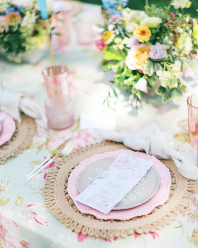 Wedding table place setting with plates, menu card, and floral arrangements