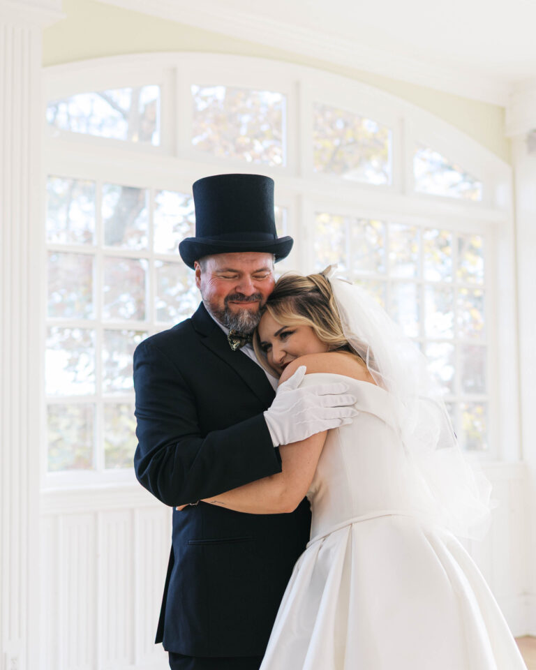 Bride sharing a first look with her father before the wedding ceremony in a bright indoor space.